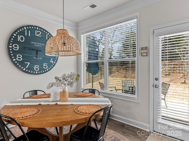 dining room featuring visible vents, wood finished floors, baseboards, and ornamental molding