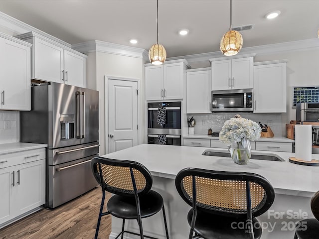 kitchen with visible vents, white cabinets, stainless steel appliances, and ornamental molding