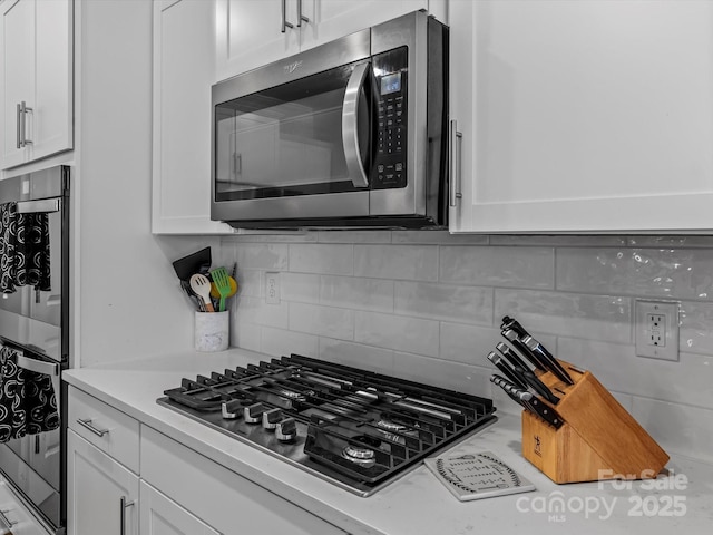 kitchen featuring stainless steel appliances, tasteful backsplash, white cabinets, and light countertops