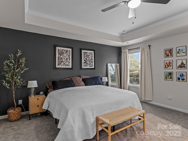 carpeted bedroom featuring baseboards, a raised ceiling, a ceiling fan, and crown molding