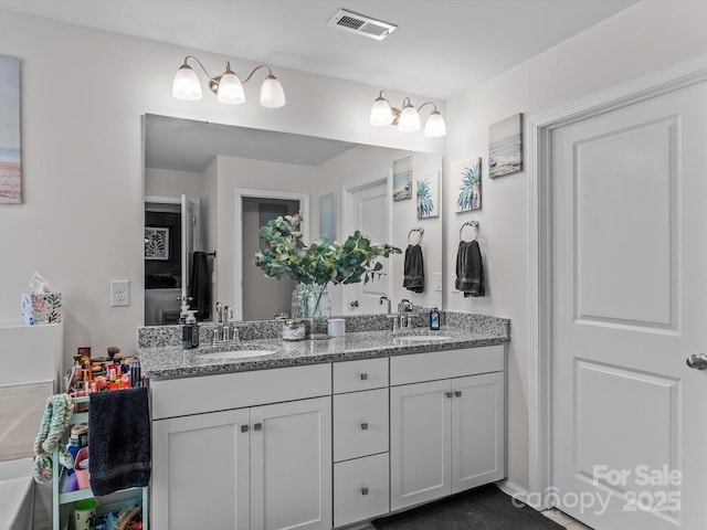 bathroom with double vanity, visible vents, and a sink