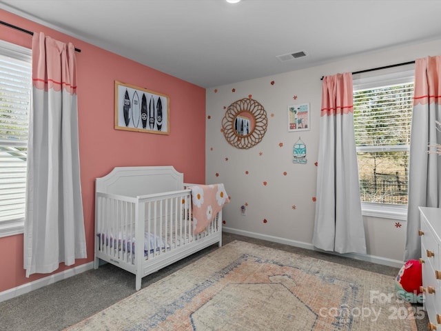 carpeted bedroom with visible vents, baseboards, and a crib