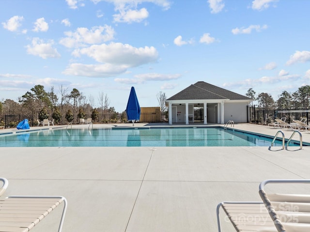 pool with a patio area, an outbuilding, and fence