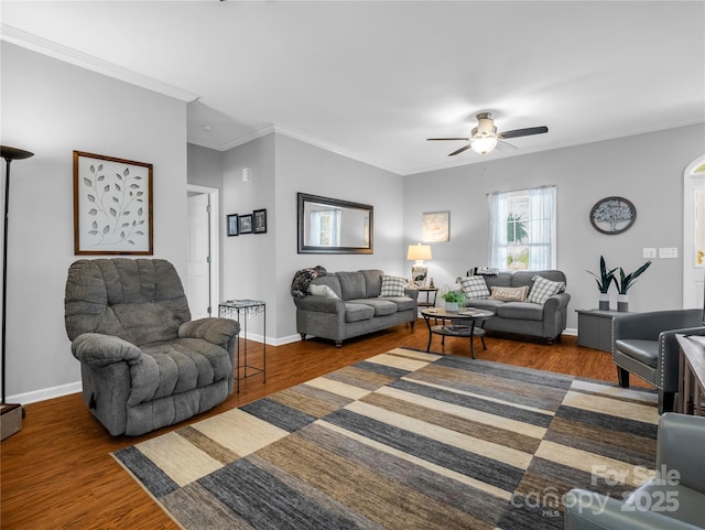 living area with baseboards, wood finished floors, ceiling fan, and ornamental molding