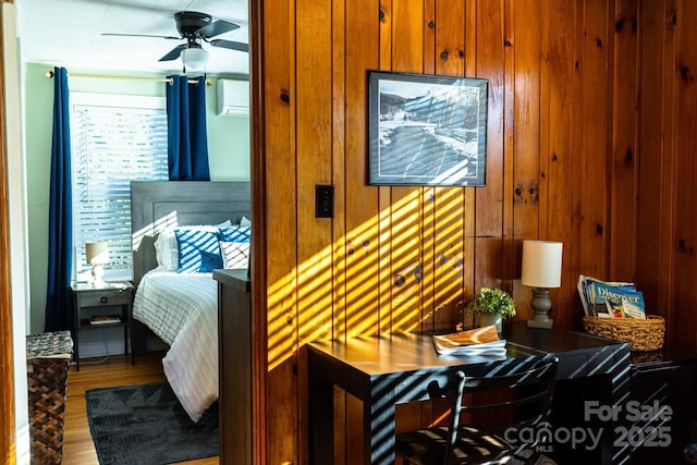 bedroom featuring wooden walls, a wall mounted AC, and wood finished floors