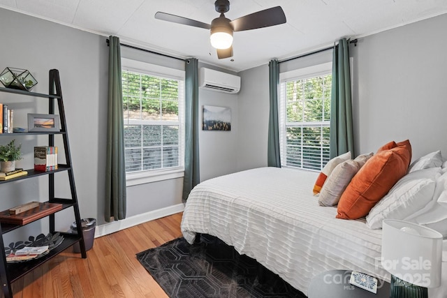 bedroom featuring ceiling fan, light wood-style floors, baseboards, and a wall mounted AC