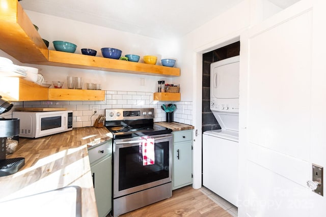 kitchen with open shelves, backsplash, stainless steel range with electric cooktop, stacked washer / drying machine, and white microwave