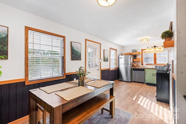 dining room featuring wood walls, wainscoting, and light wood finished floors