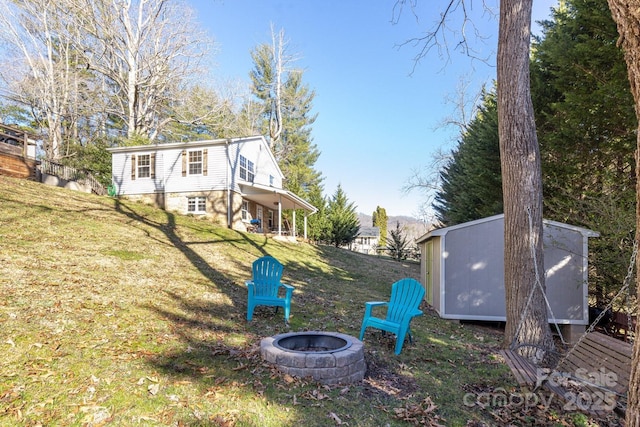 view of yard with an outdoor structure, a storage unit, and an outdoor fire pit