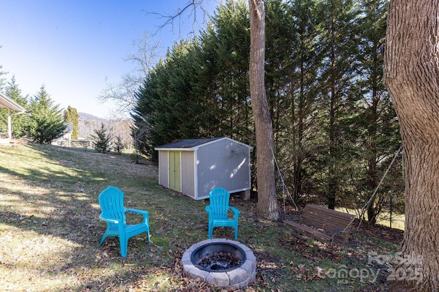 view of yard featuring an outbuilding, a shed, a mountain view, and a fire pit