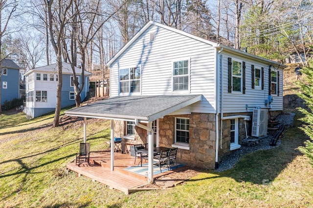 rear view of property with roof with shingles, cooling unit, a yard, a deck, and stone siding