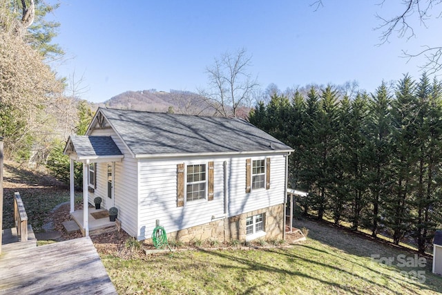 view of side of property featuring a lawn and roof with shingles