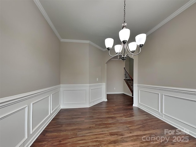 unfurnished dining area featuring dark wood-style floors, arched walkways, a chandelier, and crown molding