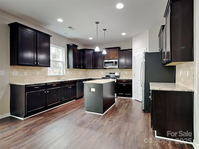 kitchen with visible vents, a center island, decorative light fixtures, dark wood-style floors, and stainless steel appliances