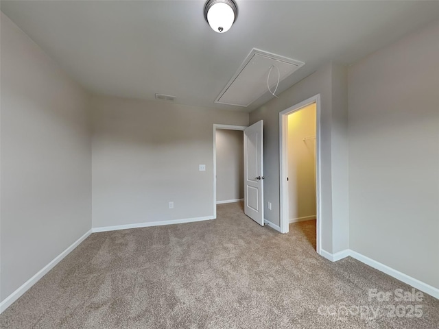 empty room featuring attic access, carpet flooring, visible vents, and baseboards