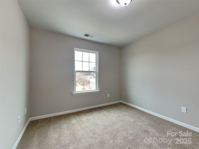 empty room featuring carpet flooring, visible vents, and baseboards