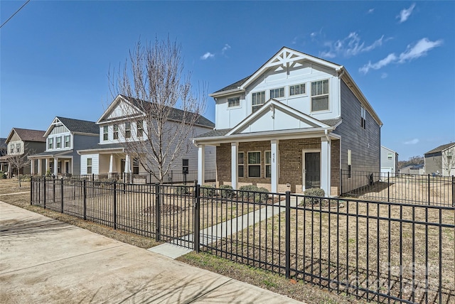 view of front of home with brick siding, a residential view, a porch, and a fenced front yard