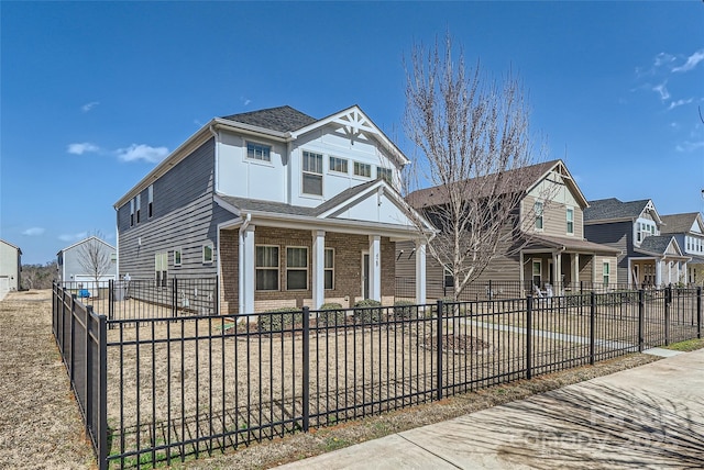 view of front of home featuring a fenced front yard, brick siding, and a porch