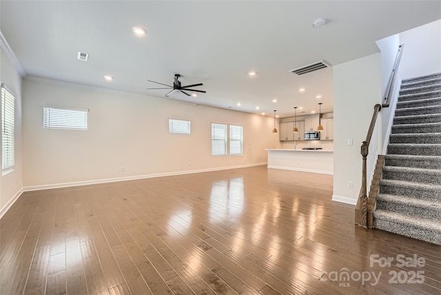 unfurnished living room featuring visible vents, a ceiling fan, wood finished floors, baseboards, and stairs