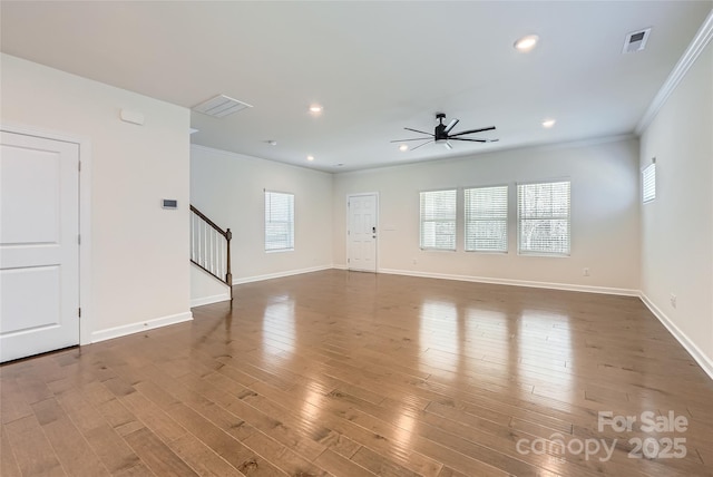 unfurnished living room featuring stairway, wood finished floors, ceiling fan, and crown molding