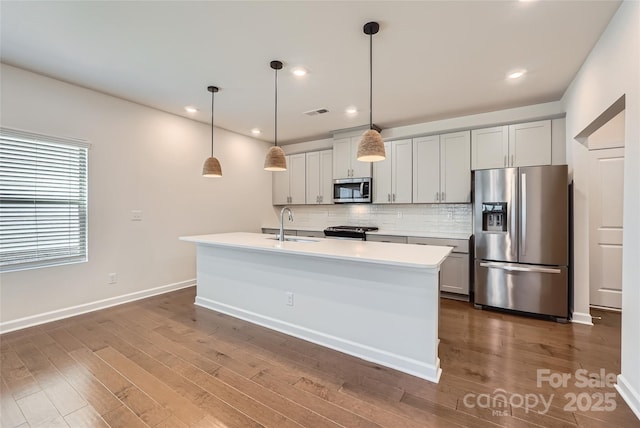 kitchen with a sink, backsplash, light countertops, stainless steel appliances, and dark wood-style flooring