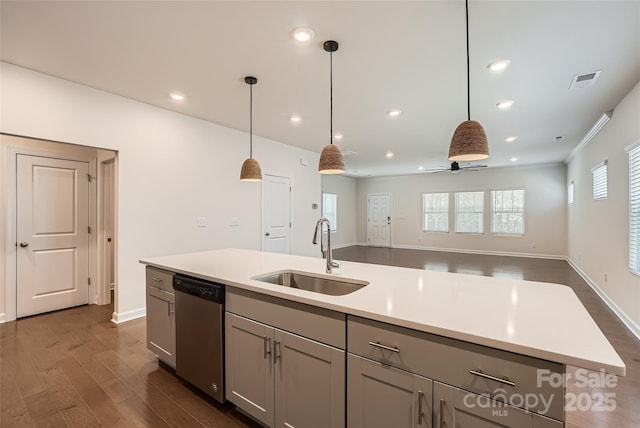 kitchen featuring a healthy amount of sunlight, a sink, dark wood-type flooring, light countertops, and stainless steel dishwasher