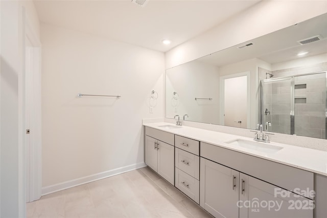 bathroom featuring double vanity, a shower stall, baseboards, and a sink