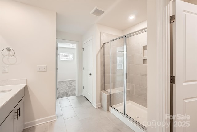 bathroom featuring tile patterned floors, visible vents, a stall shower, baseboards, and vanity