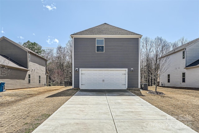 view of side of home with cooling unit, a garage, roof with shingles, and driveway