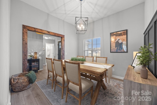 dining area with a chandelier, light wood-type flooring, and baseboards