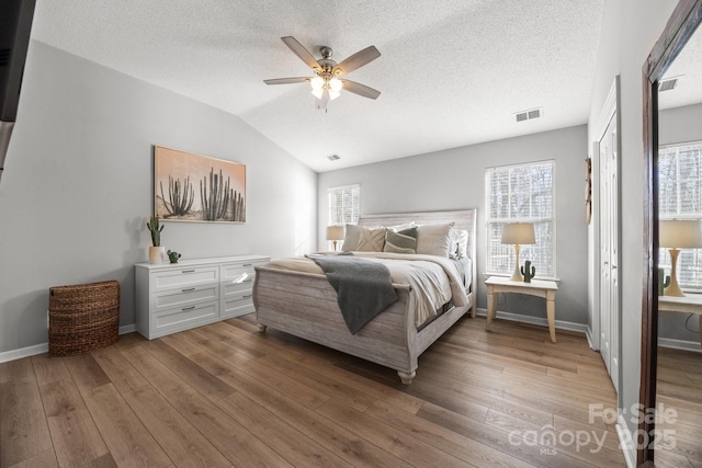 bedroom featuring baseboards, visible vents, wood-type flooring, and lofted ceiling