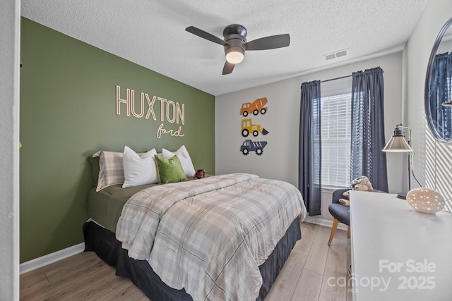 bedroom featuring a ceiling fan, baseboards, visible vents, and light wood finished floors