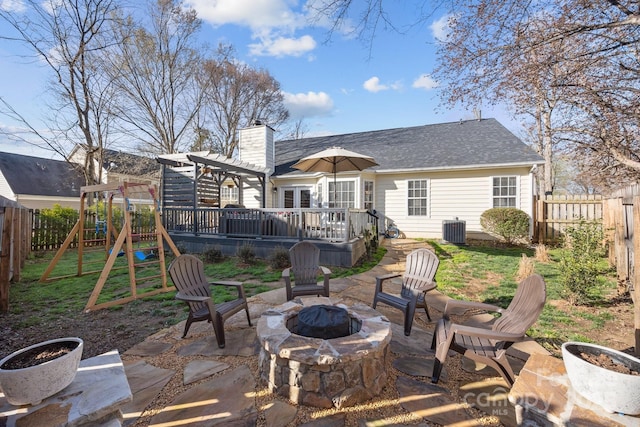 back of property featuring a playground, a fire pit, a lawn, and a fenced backyard