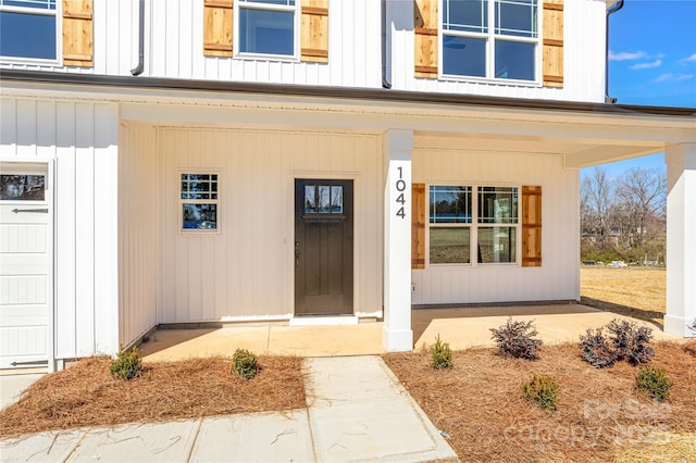 doorway to property featuring board and batten siding and covered porch