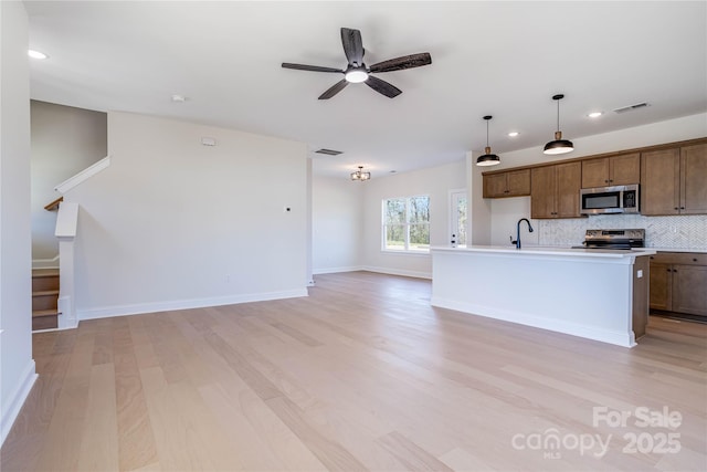 kitchen featuring tasteful backsplash, open floor plan, appliances with stainless steel finishes, and light wood-type flooring