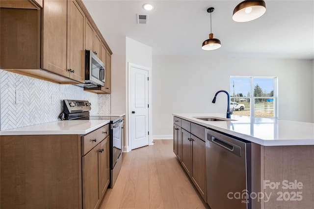 kitchen featuring a sink, stainless steel appliances, visible vents, and light countertops