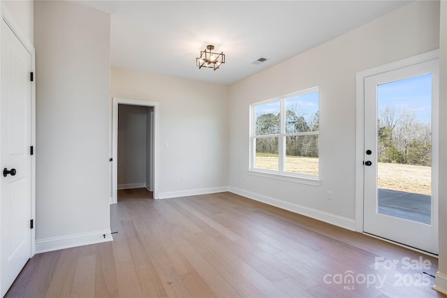 unfurnished dining area with visible vents, an inviting chandelier, baseboards, and wood finished floors