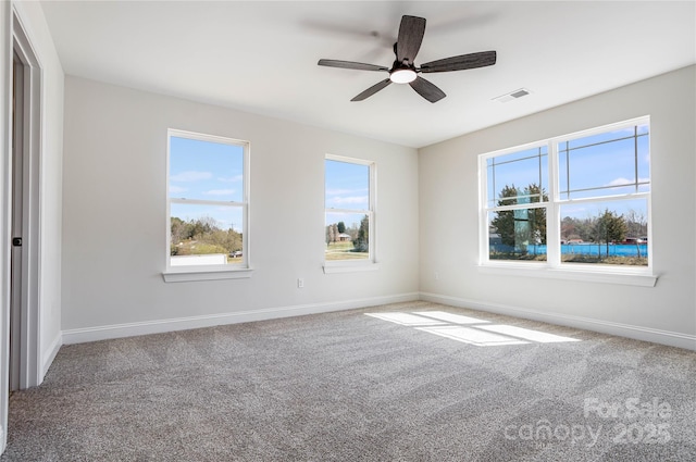 empty room with visible vents, baseboards, carpet, and a ceiling fan