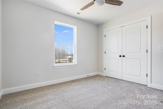 unfurnished bedroom featuring visible vents, a closet, carpet flooring, baseboards, and ceiling fan