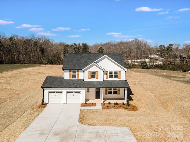 modern farmhouse featuring an attached garage, concrete driveway, roof with shingles, and a view of trees