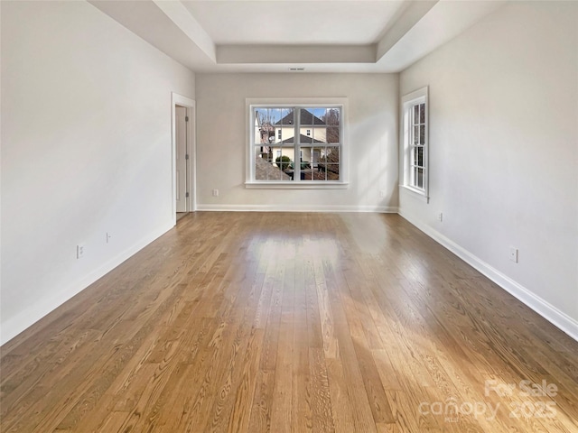 empty room with a raised ceiling, baseboards, and hardwood / wood-style floors