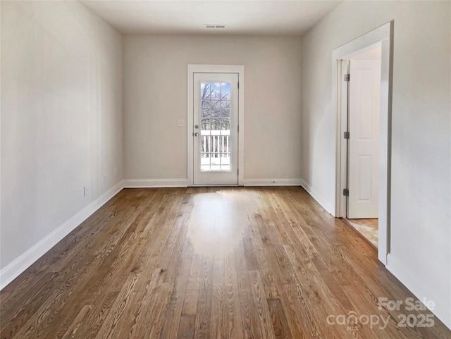 spare room featuring visible vents, baseboards, and wood finished floors