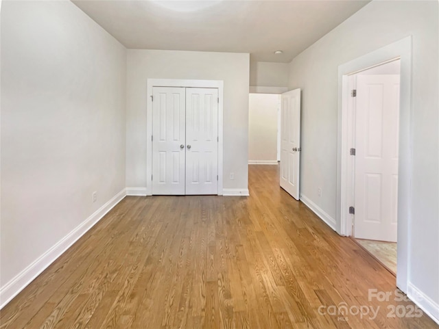 unfurnished bedroom featuring a closet, baseboards, and light wood-style flooring