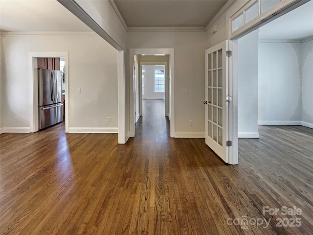 unfurnished room featuring dark wood finished floors, crown molding, and baseboards