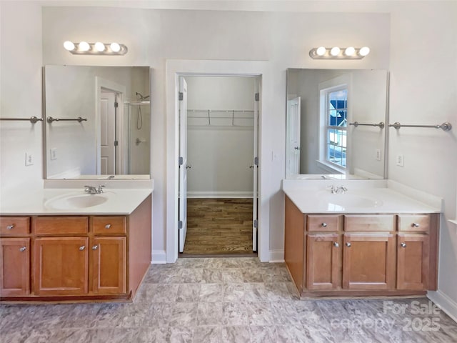 full bathroom featuring a spacious closet, two vanities, a stall shower, and a sink