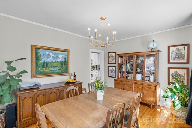 dining area with crown molding, light wood-type flooring, and a chandelier