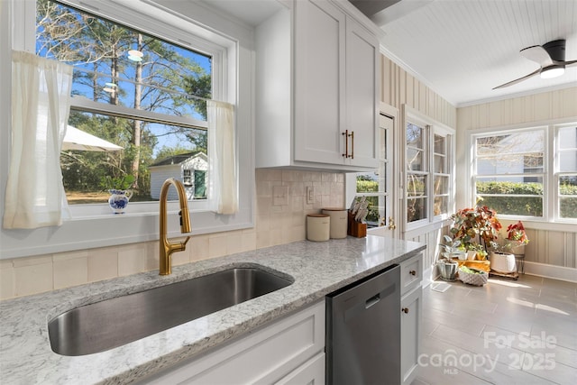 kitchen featuring light stone counters, white cabinetry, a sink, stainless steel dishwasher, and tasteful backsplash