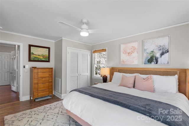 bedroom with wood finished floors, visible vents, baseboards, a closet, and crown molding