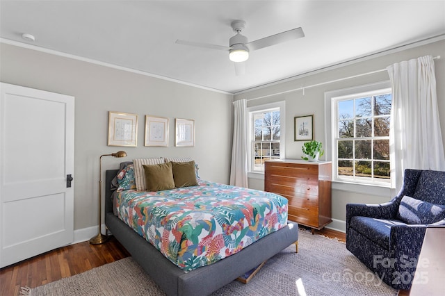 bedroom with a ceiling fan, crown molding, baseboards, and wood finished floors