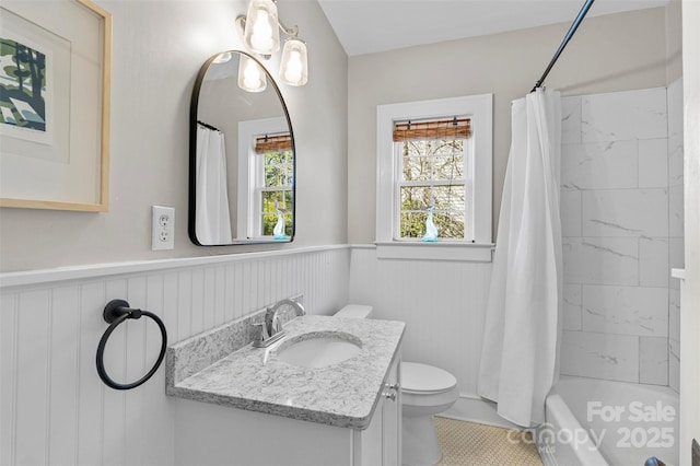 full bath featuring a wainscoted wall, toilet, vanity, and shower / bathtub combination with curtain